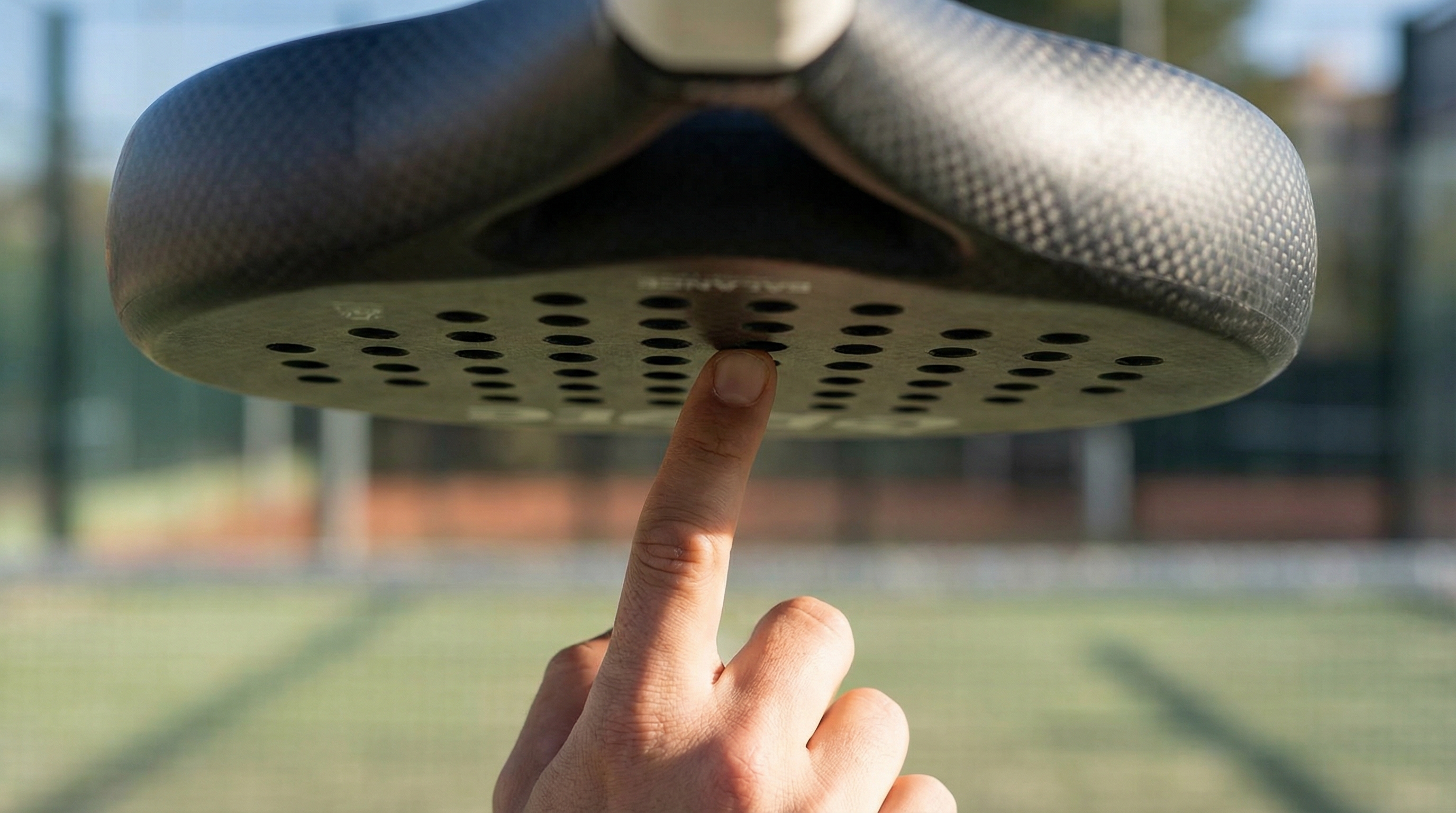 A finger balancing a padel racket at its center point