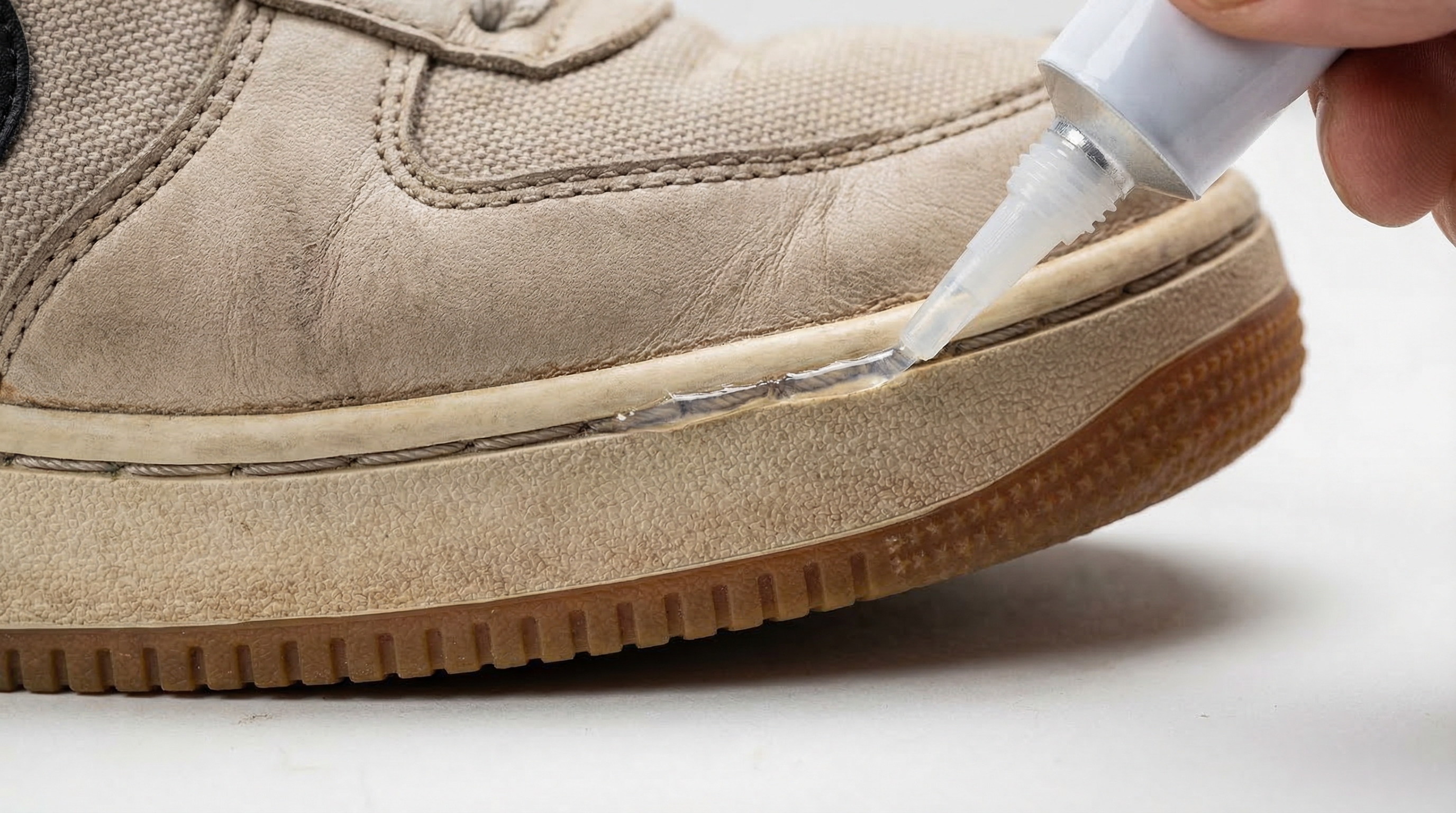 Applying specialized footwear adhesive (Shoe Goo) into a small gap where the sole is delaminating from the upper.