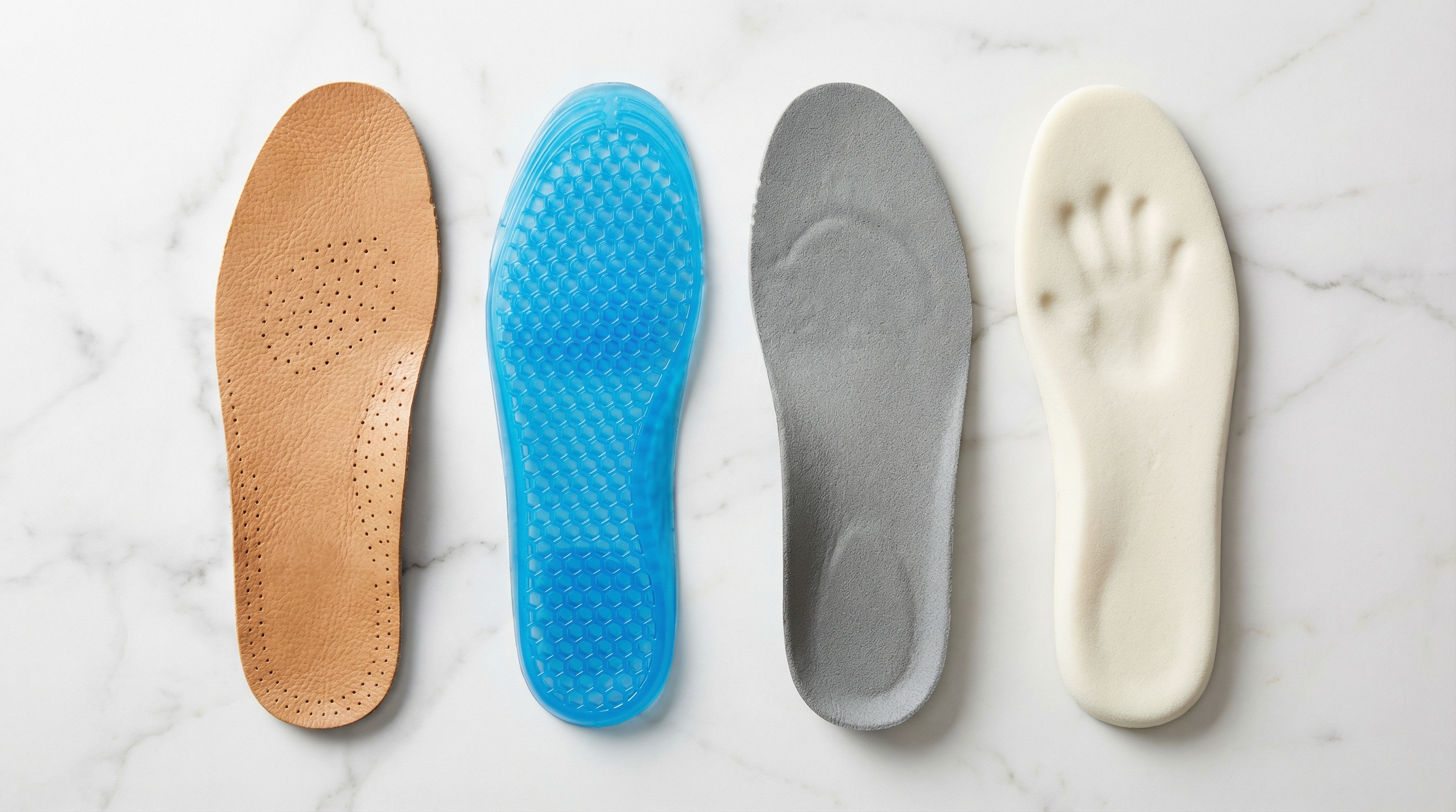 A macro comparison shot of four different shoe insole materials: leather, blue gel, grey foam, and white memory foam, laid out on a marble surface.