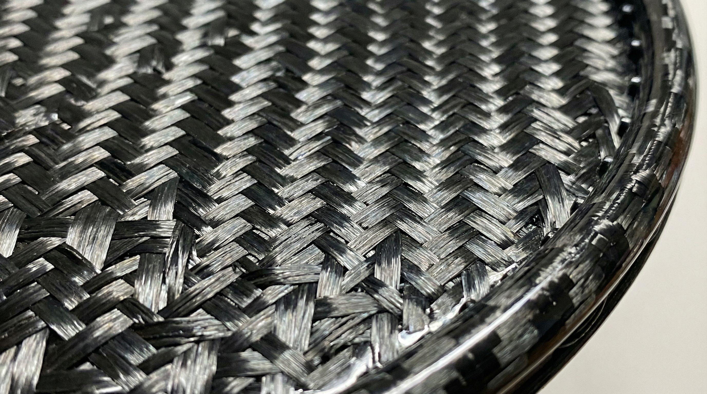 Close-up photorealistic image of a 12K carbon fiber weave texture on a racket face