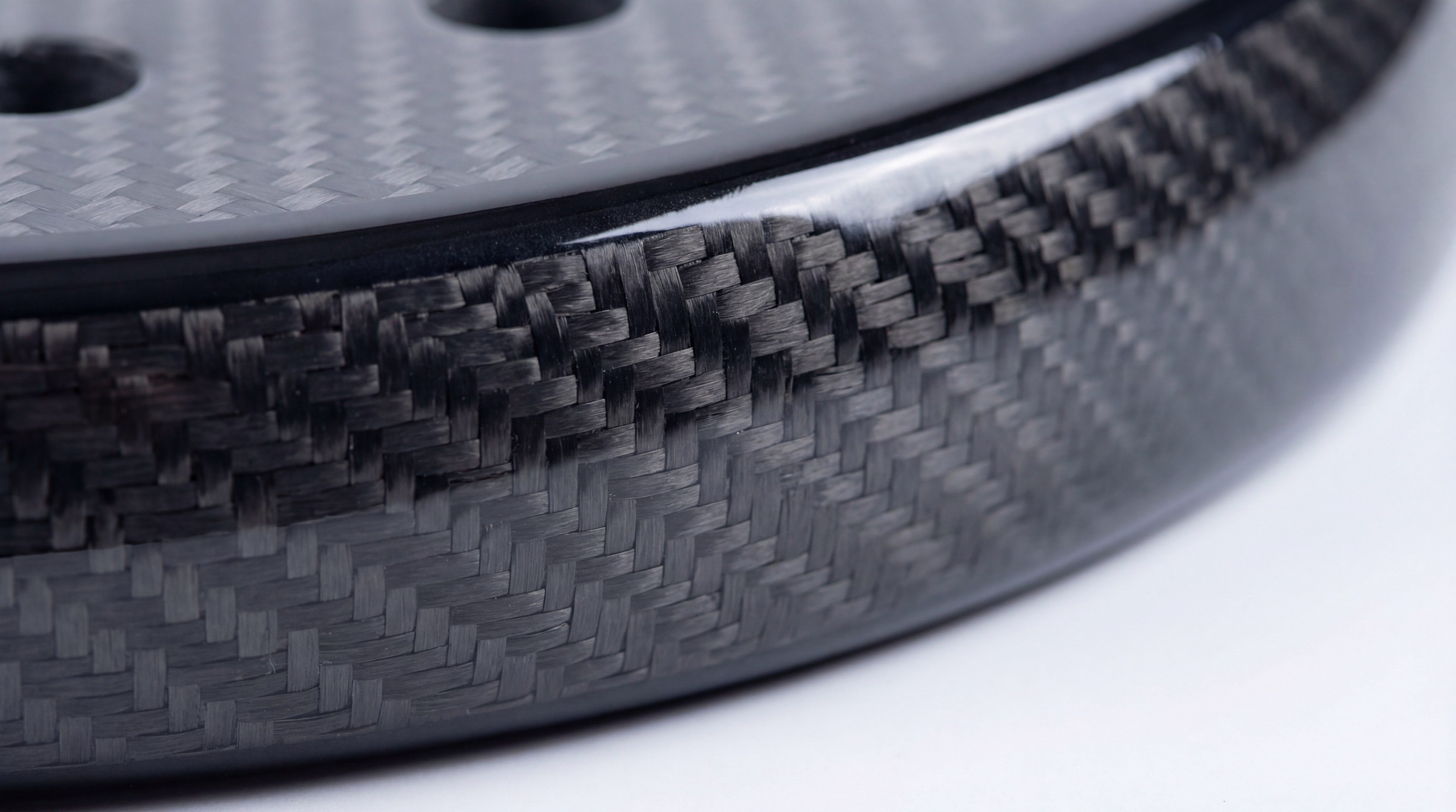 Macro close-up of a 12K carbon fiber weave on a racket frame showing the intricate pattern
