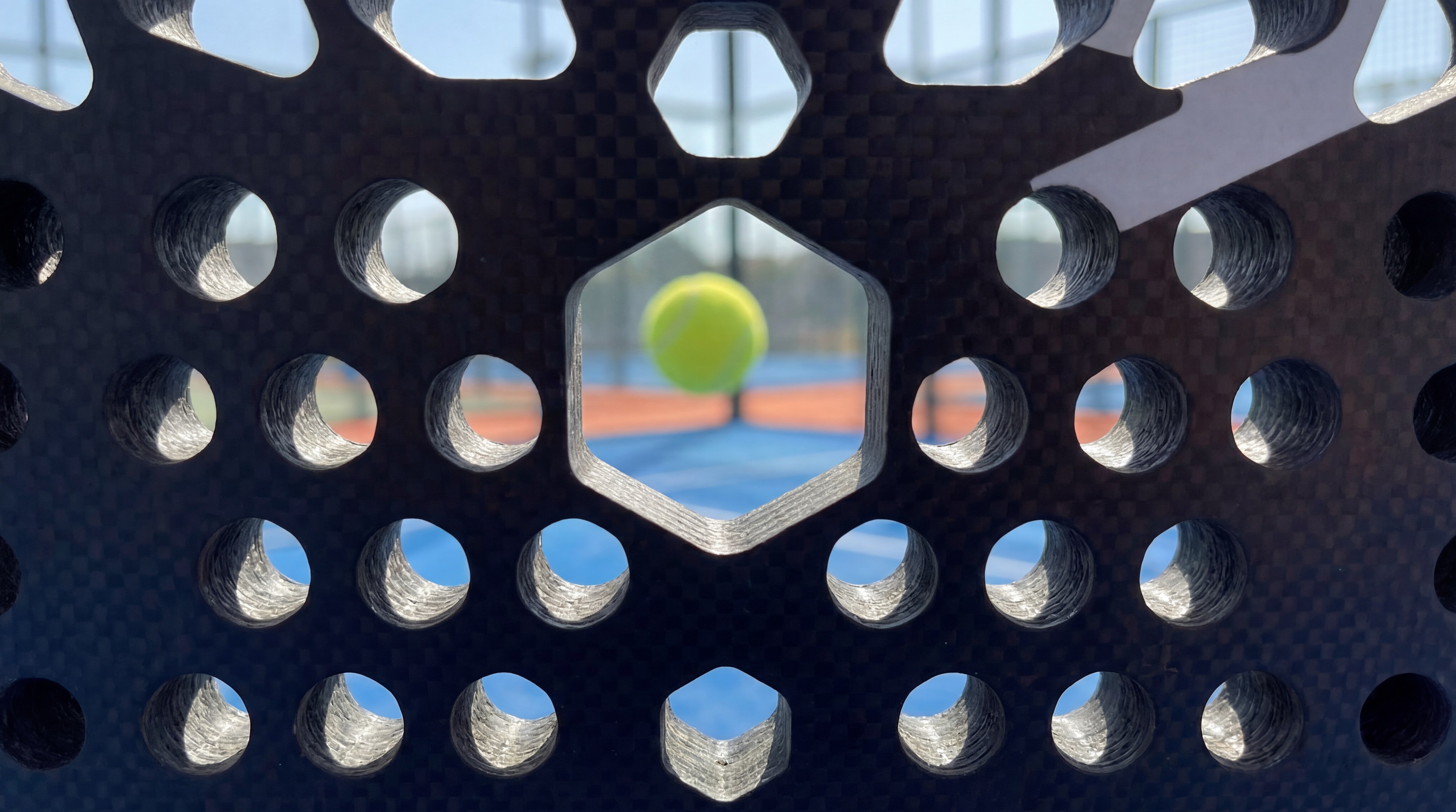 artistic close-up looking through the holes of a padel racket