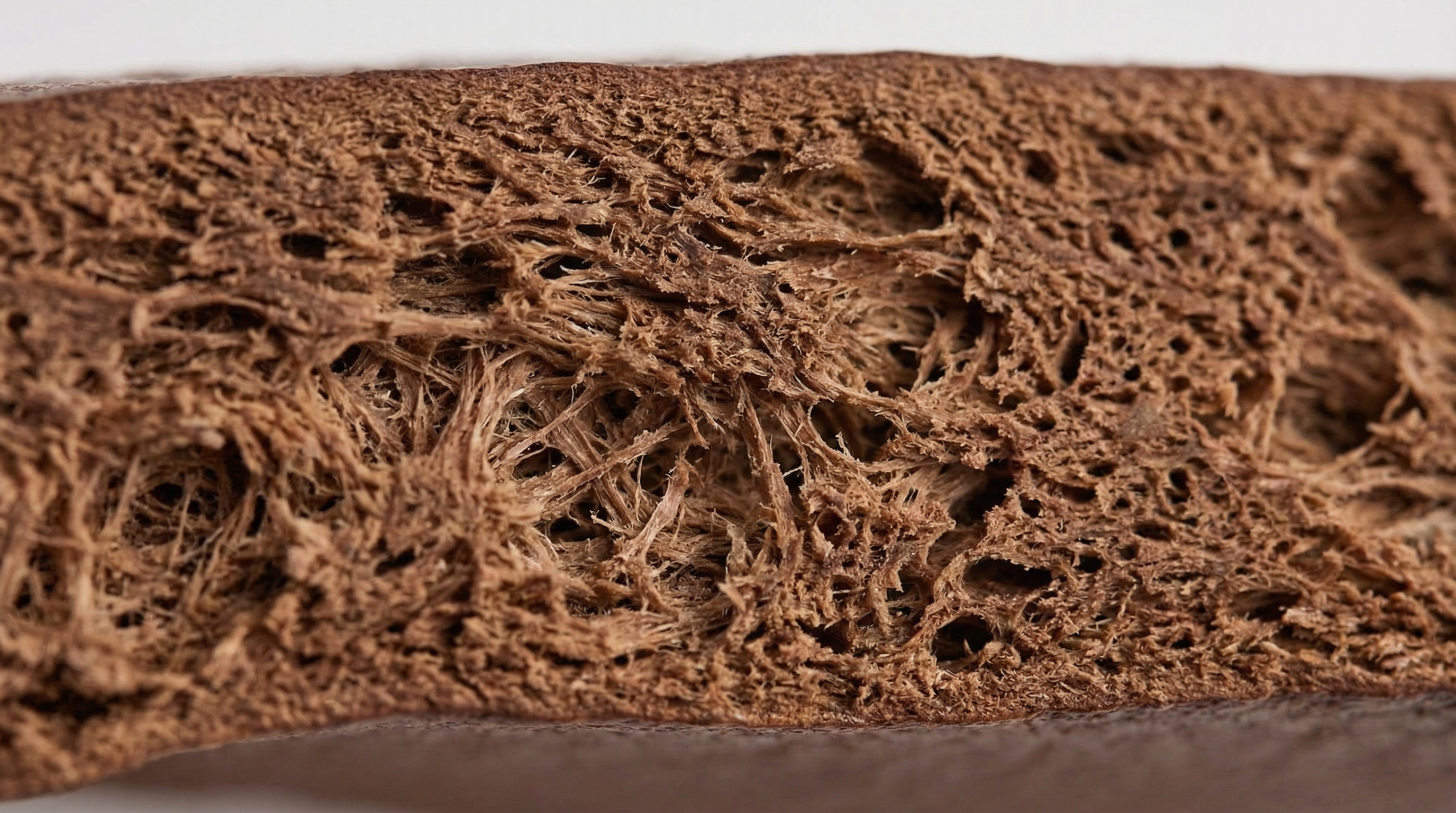 Macro photography style, extreme close-up angle, showing the cross-section of full-grain leather fibers. The image focuses on the intricate, interlacing collagen network of the hide, highlighting the porous texture and natural organic patterns. Neutral studio lighting emphasizes the fibrous depth and organic warmth.