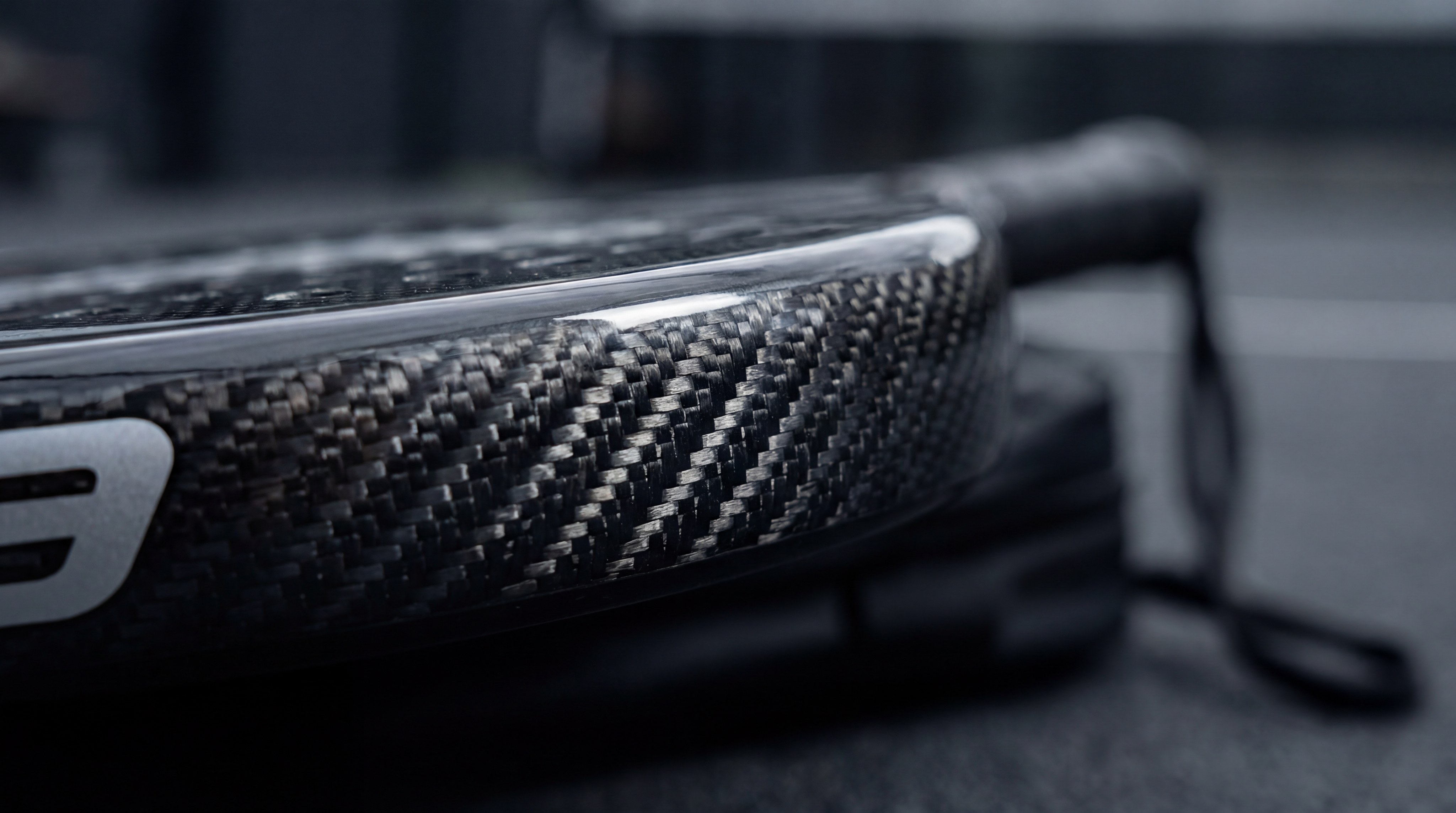 macro photography of a padel racket frame showing carbon fiber weave