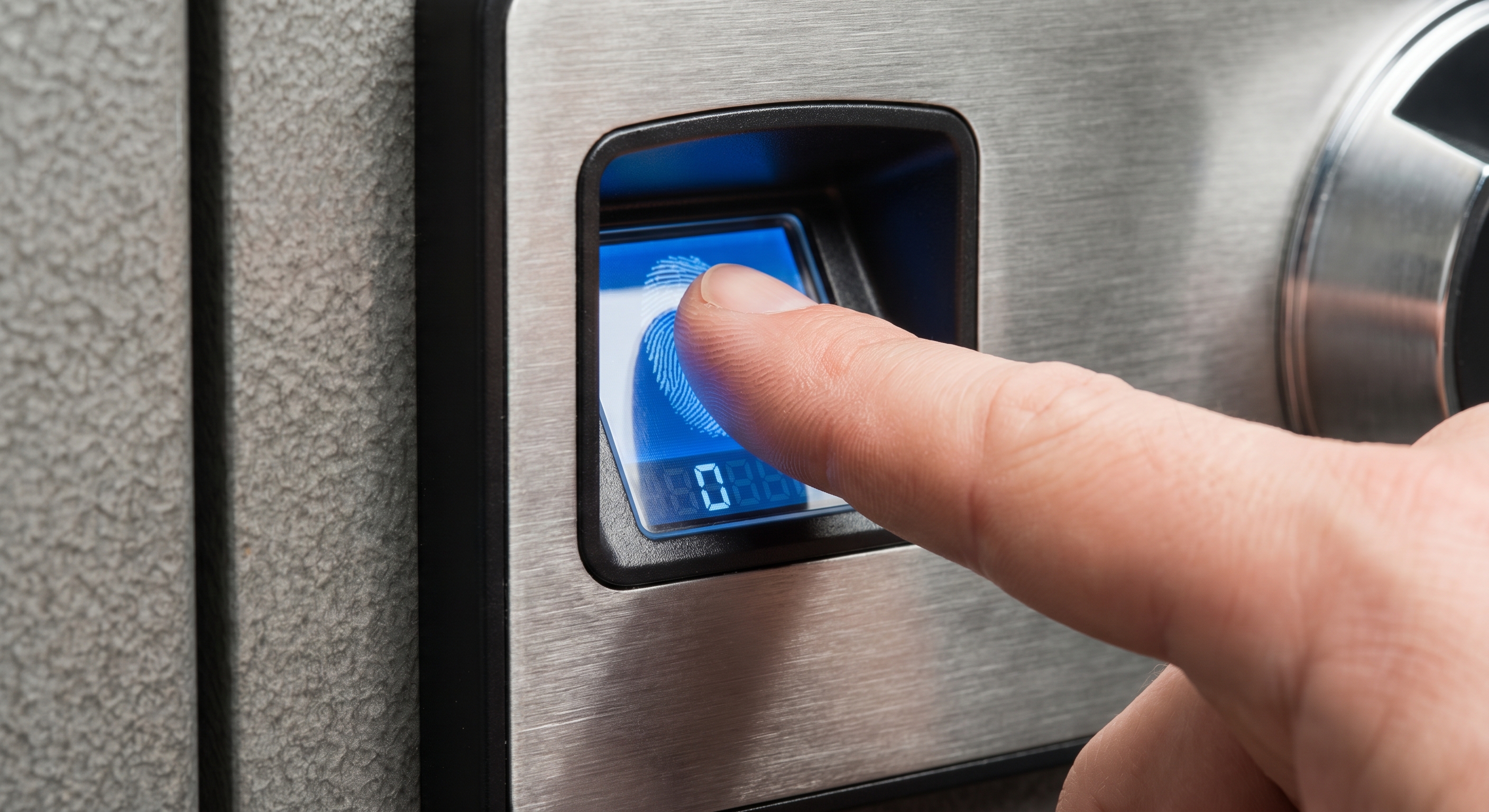 A finger pressing against a blue-lit biometric scanner on a steel safe door